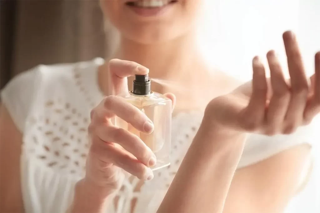 Kobieta rozpylająca perfumy na nadgarstek.